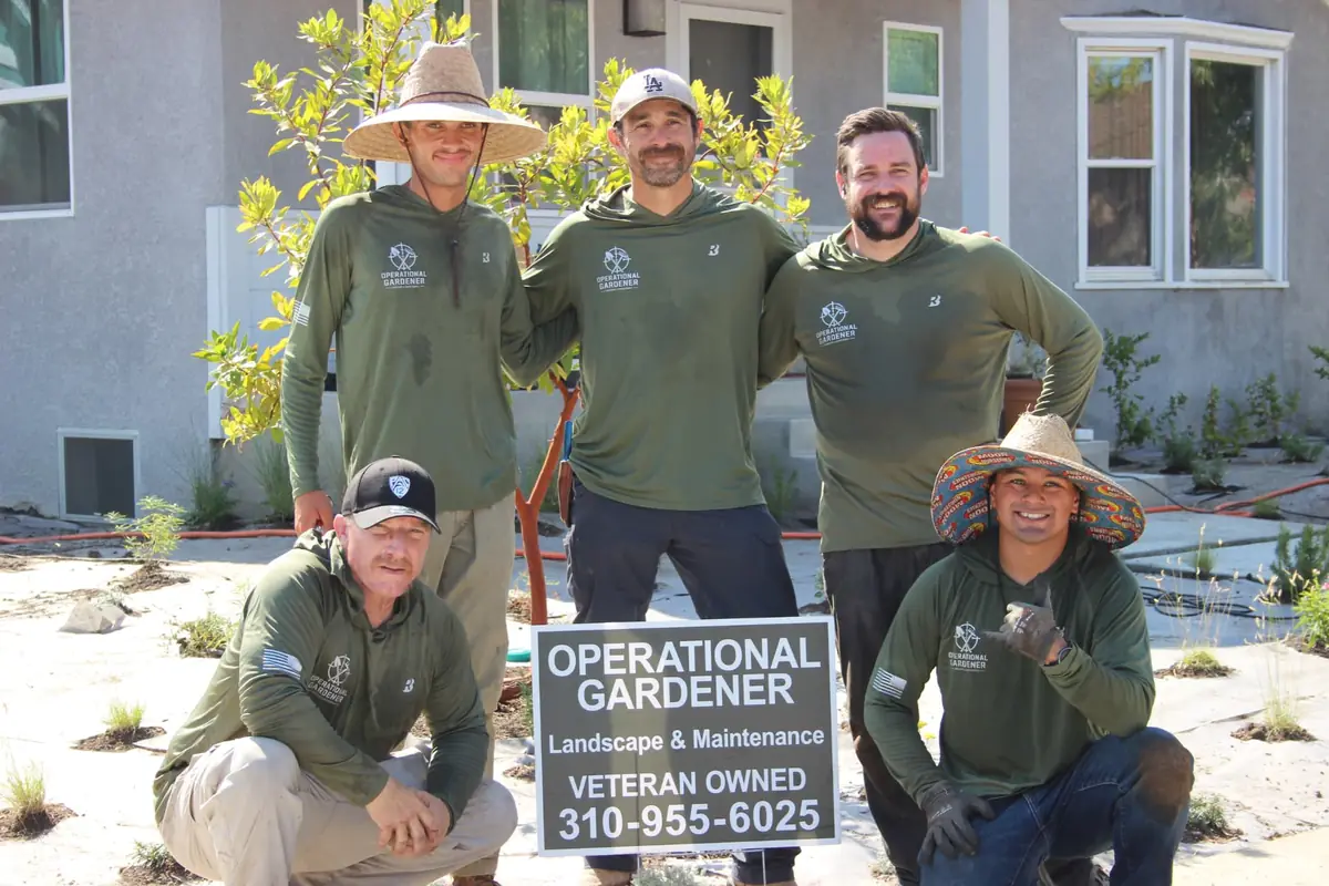 The Operational Gardener crew standing behind their veteran-owned landscape and maintenance company sign on a finished Southern California job site